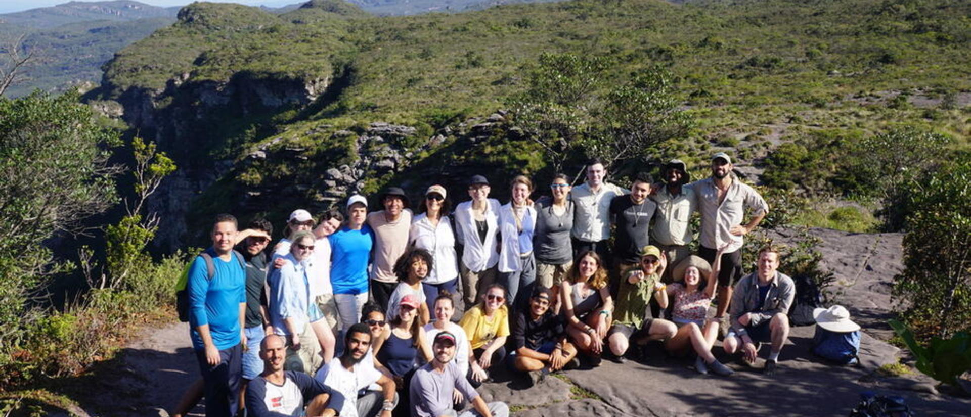 A group of researchers in the field, behind them a scenic mountain view.