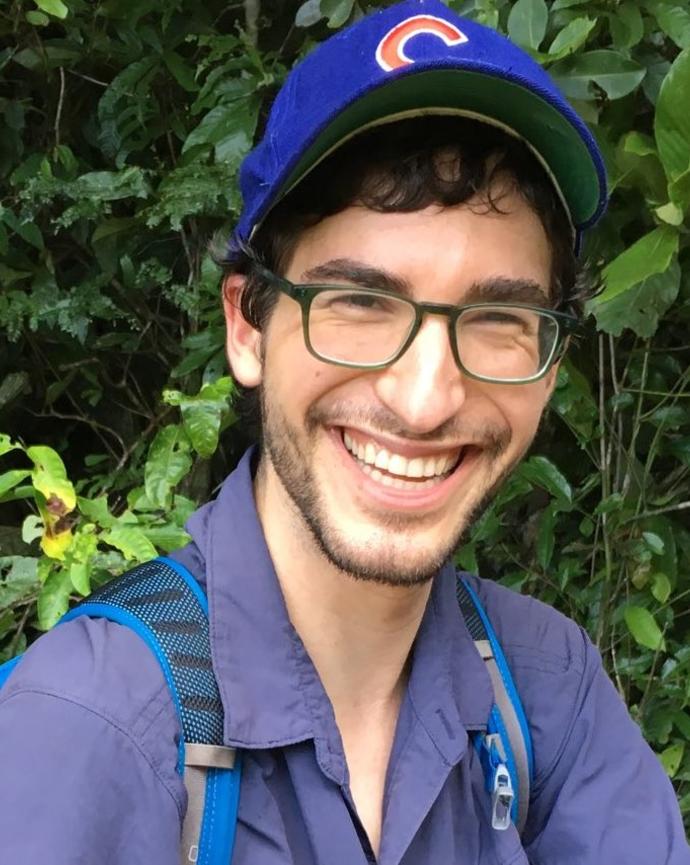 a man with glasses facial hair wearing a chicago baseball cap smiles